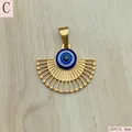 Detailed view of a gold fan-shaped evil eye pendant on a light wood surface. - Style C (Fan Gold Base)
