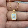 Detail view of a Taurus zodiac necklace with white shell inlay on a gold bead chain - Taurus