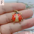 Primer plano de un colgante de mariquita de esmalte rojo con circonitas en un dedo para escala. - 22.3*24.8mm