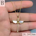 Vista de un collar de libélula dorada con alas de nácar blanco y circonitas blancas. - Libélula