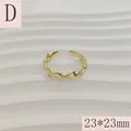 Detailed macro view of a gold-plated wavy geometric open ring on a white textured background - Wavy Line Style (D) / 23*23mm (Adjustable Open) / Gold