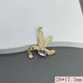 Detailaufnahme eines goldenen Kolibri-Anhängers mit rosa Steinen und Zirkonia-Inlay. - Rosa