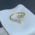 Detailed view of adjustable gold-tone ring with two zircons and a white pearl accent. - Double Zirconia Pearl Style (A) / Adjustable Open / Gold