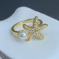 Close-up of golden starfish ring with micro-set zircons and a white pearl accent - Starfish Pearl Style (C) / Adjustable Open / Gold
