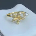 Detailaufnahme eines eleganten goldenen Blumenrings mit funkelnden Zirkonia und Perle. - Blume Perle Stil (E) / Einstellbar Offen / Gold