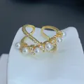 Vista detallada de un elegante anillo cruzado de oro con perlas y circonitas. - Estilo Micro-incrustado Multiperla de Envoltura Cruzada