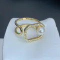 Primer plano de un anillo geométrico dorado con una perla blanca y circonitas. - Estilo Perla Micro-incrustada Octágono Geométrico