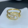 Detalle macro de un anillo de imperdible dorado con perla y detalles de circonita. - Estilo Circonia Pavé Perla Alfiler de Gancho