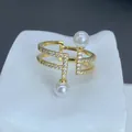 Vista macro de un anillo de doble banda dorado con perlas blancas y circonitas brillantes - Estilo Pavé Perla Vertical de Doble Capa