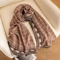 Close-up of elegant silk-wool blend scarf with brown grid and paisley border pattern - Double-Sided Plaid Elegance