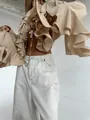 Close-up of elegant beige long-sleeve blouse with oversized ruffles and French style flair. - S / Tops / Khaki