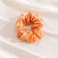 Large elegant orange silk scrunchie with smooth satin finish on white draped fabric - Orange