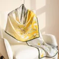 Elegant mulberry silk scarf with yellow and white floral print draped on a white chair. - 55x170cm / Warm Yellow Buds (FHZ25-9579-1)
