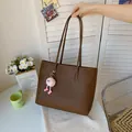Detail shot of a brown vintage tote bag featuring a pink fluffy charm held by hand - With Pendant / Coffee