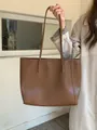 Close-up detail of a vintage brown large capacity leather tote bag held by a fashion model - Coffee Brown