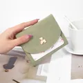 Short trifold women's wallet in light green featuring a cute gold bear emblem design - Green