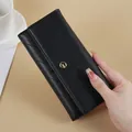 Elegant black quilted women's long wallet clutch with gold metal emblem hand-held view - Black