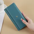Elegant teal blue long wallet for women featuring a minimalist quilted design held by hand - Blue
