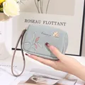 Main tenant une petite pochette en cuir PU bleu clair avec motif de feuilles - Bleu
