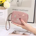 Vue détaillée d'un porte-monnaie rose en similicuir avec breloque oiseau et feuilles - Vieux rose