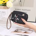 Gros plan d'un porte-monnaie noir en similicuir avec breloque oiseau et motif feuilles porté. - Noir