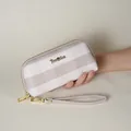 Primo piano di una borsa a mano a righe da donna con dettagli in metallo dorato tenuta in mano - Cammello