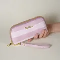 Primo piano di una mano che tiene una pochette a righe rosa e bianche con cinturino - Rosa