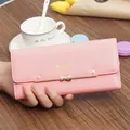 Detailed close-up of a pink long wallet featuring a golden bow and elegant flower rivet details - Pink
