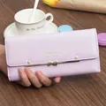 Close-up of lavender long wallet featuring a gold bow accent and delicate flower studs. - Purple