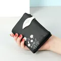 Compact black soft leather bi-fold wallet featuring daisy floral print and leaf snap - Black