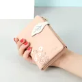 Small pink bi-fold wallet with daisy prints and a leaf-shaped button closure - Pink