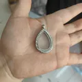 Vista detallada de un colgante relicario de gota de agua plateado con pedrería fina - Estilo de Strass