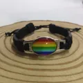 Nahaufnahme eines handgefertigten Regenbogen-Lederarmbands auf einer Holzscheibe - Schwarz