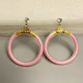 Macro-weergave van fonkelende roze glitter jelly oorringen met goudkleurige getextureerde accenten - Roze