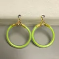 Detailopname van neon groene glitter gevulde oorringen met goudkleurige metalen accenten - Lichtgroen