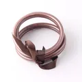 Dettaglio di braccialetti jonc bouddhiste marroni in silicone flessibile con un nastro. - Caffè