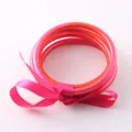 Dettaglio bracciali in tubo di silicone traslucido rosa e arancione con fiocco di seta - Rosso rosa