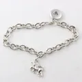 Macro detail view of a polished silver chain bracelet featuring a unicorn charm and snap button - Unicorn Pendant / Yellow