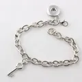 Detail of a DIY snap button charm bracelet with a silver-toned key pendant and link chain. - Key Fob / Green
