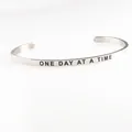 Detailansicht der Gravur 'ONE DAY AT A TIME' auf dem 4mm Edelstahl-Armreif - Ein Tag nach dem anderen