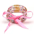 Primo piano di 5 bracciali jelly con perline colorate e un elegante fiocco di nastro rosa - Set a 5 Strati (JB618) / Rosa Multicolore