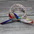 Detalle de un brazalete de silicona multicapa con cuentas de colores y un lazo de arcoíris - Arcoíris