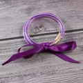 Detail view of purple silicone jelly bangles filled with glitter and tied with a ribbon - 3-Layer Set / February Purple