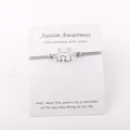 Detail van verzilverde Autism Awareness puzzel armband met grijs waskoord en een berichtkaart - Grijs