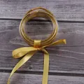 Detail of 7-layer gold glitter silicone jelly bangles set tied with a yellow silk ribbon. - Gold