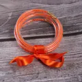 Set of five vibrant orange silicone bead bracelets tied with a matching satin ribbon bow - 5 Pieces / Orange