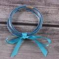 Vue détaillée de trois joncs en silicone bleu pailleté avec un ruban en satin. - Ensemble à 3 couches / Bleu ciel