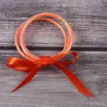 Détail de trois joncs jelly orange pailletés attachés par un ruban en satin. - Ensemble à 3 couches / Orange