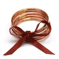 Close-up of five orange glitter silicone jelly bangles tied with a dark red satin bow - 5 Pieces / Rose Gold