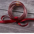 Close-up of red glitter-filled silicone jelly bangles tied with a matching satin ribbon. - Red